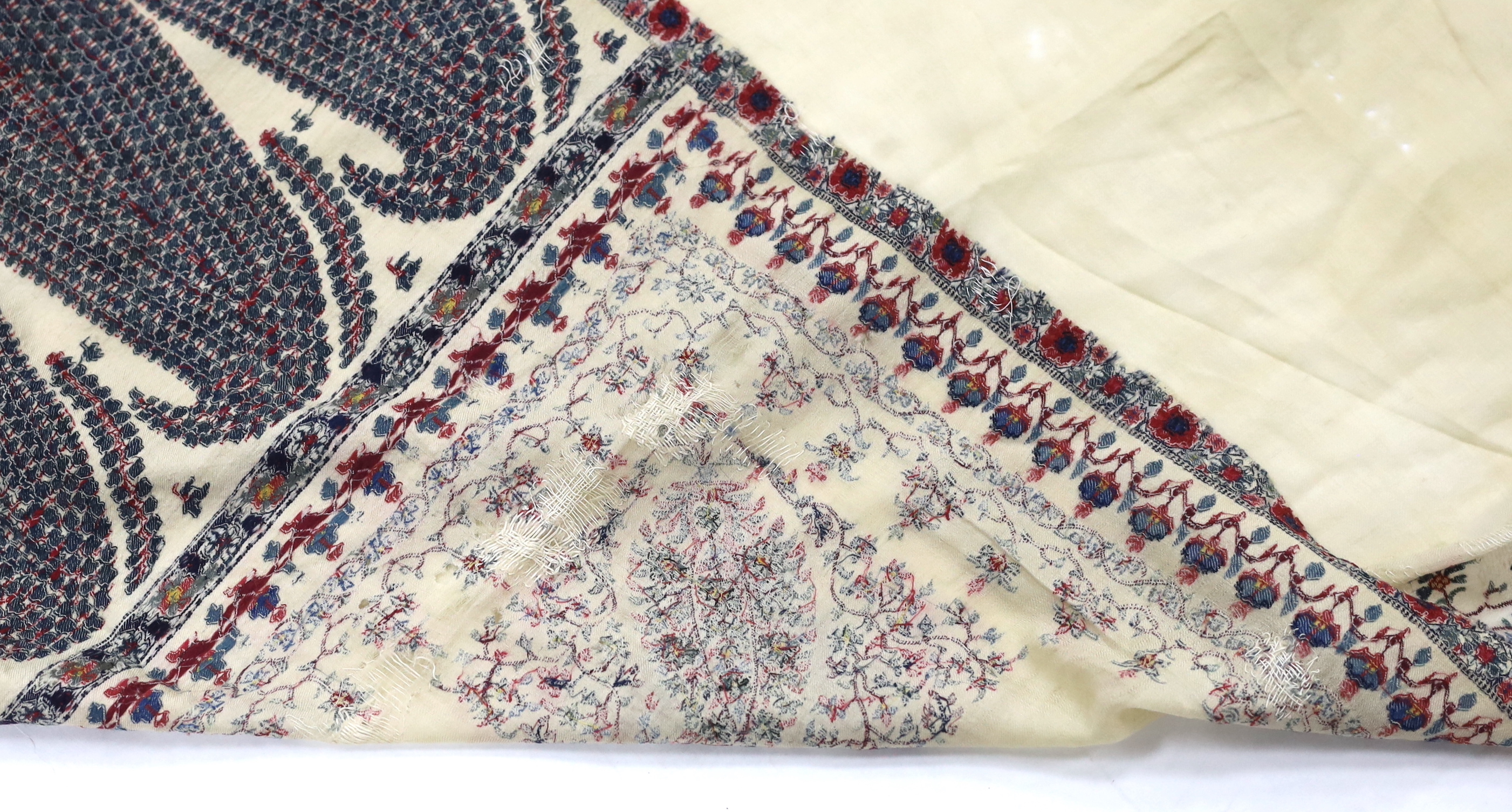 A 19th century fine cream woven Kashmiri shawl with blue and red teardrop design borders, an early 20th century gold satin pelmet with spot motifs of peacocks and flowers, 204cm long x 71cm high and a length of silk with
